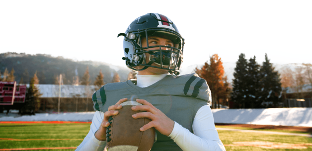 Football player holding a football on a field